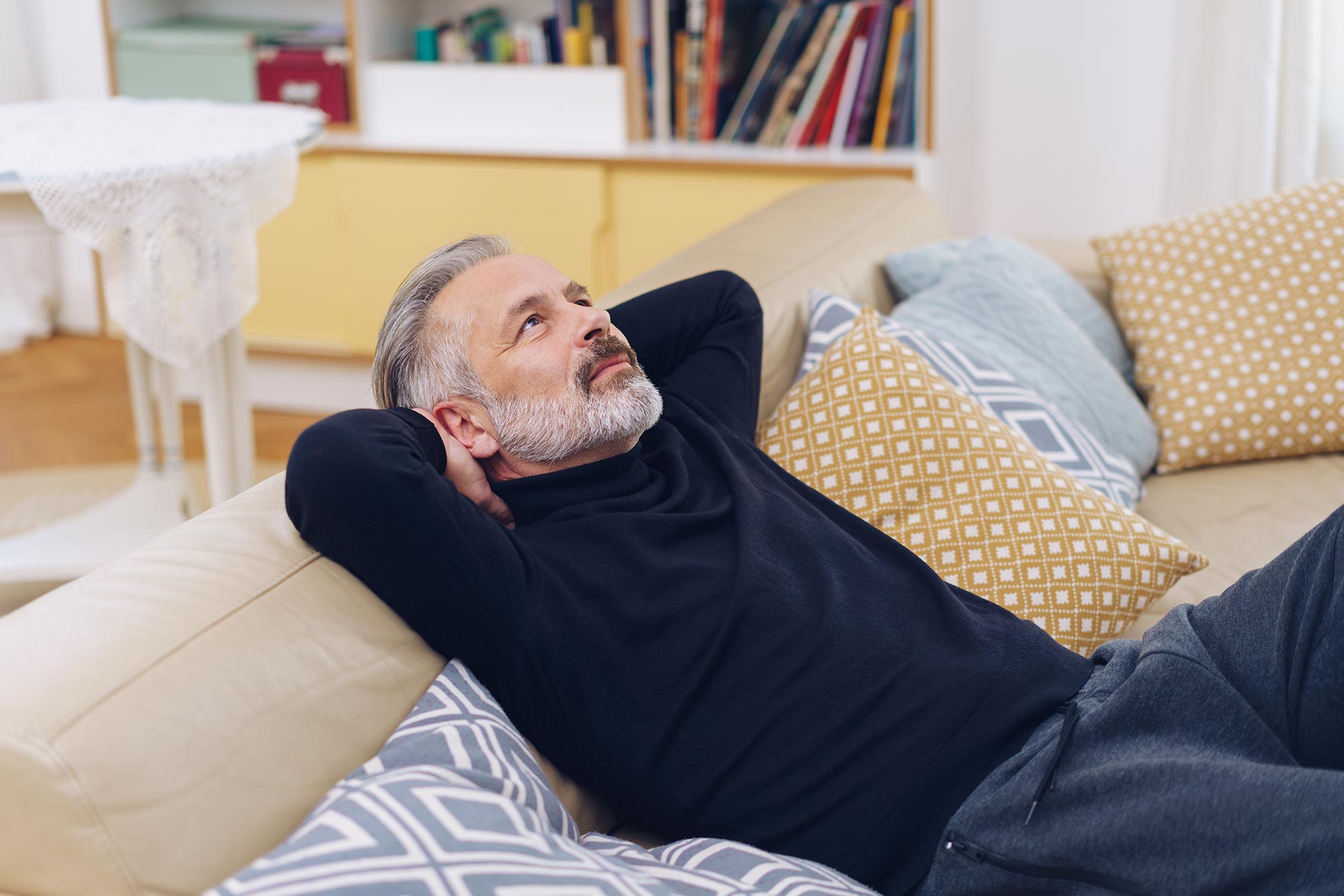 Older man pondering while laying on couch