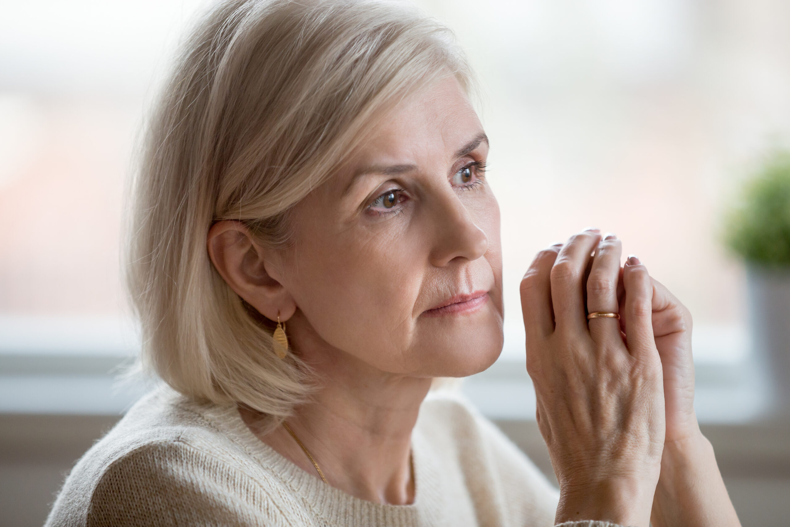 Older blonde haired woman sitting alone deep in reflection
