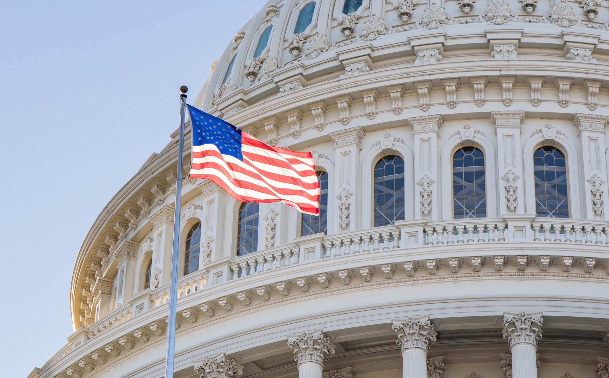 American flag waving in front of US capitol building dome